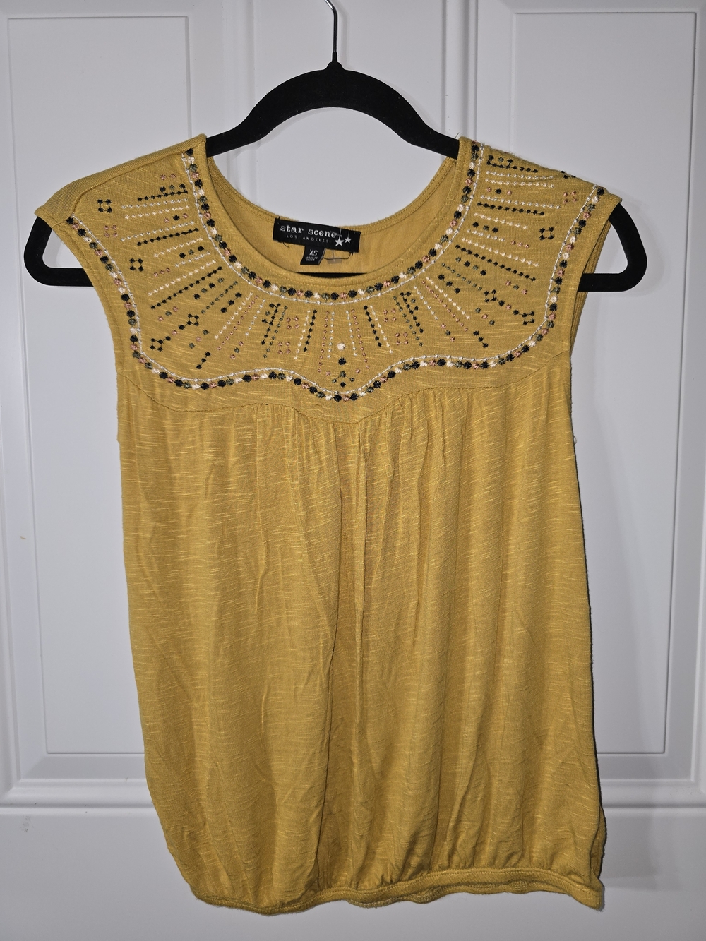 Sleeveless blouse with embroidered flowers on the neckline